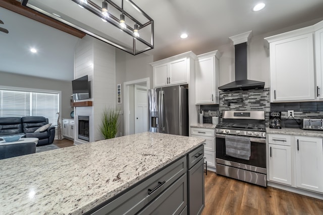 kitchen featuring tasteful backsplash, wall chimney exhaust hood, appliances with stainless steel finishes, open floor plan, and dark wood-type flooring