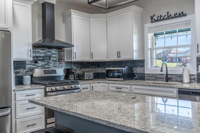 kitchen featuring stainless steel appliances, a sink, decorative backsplash, and wall chimney exhaust hood