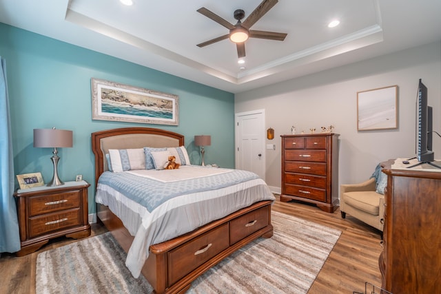 bedroom featuring light wood-type flooring, a tray ceiling, baseboards, and recessed lighting