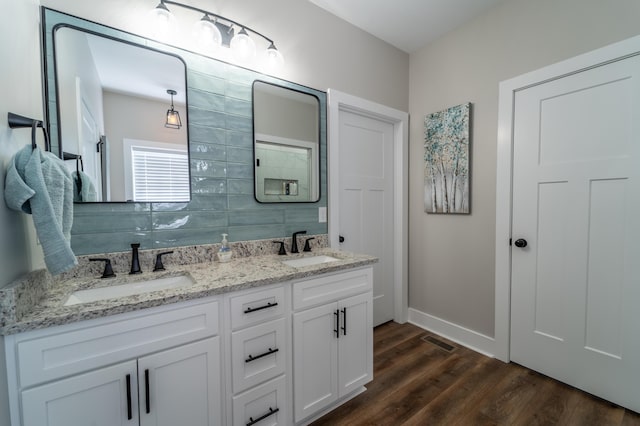 bathroom featuring double vanity, baseboards, a sink, and wood finished floors