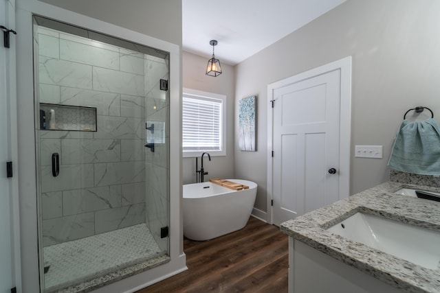 full bathroom featuring double vanity, a soaking tub, wood finished floors, a shower stall, and a sink