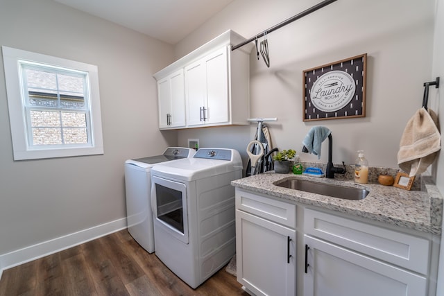 laundry room featuring dark wood-style floors, washing machine and clothes dryer, cabinet space, a sink, and baseboards