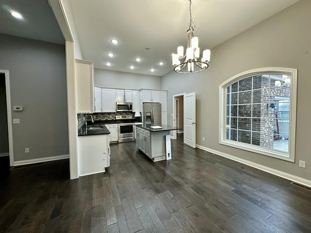 kitchen featuring a sink, visible vents, appliances with stainless steel finishes, a center island, and dark countertops