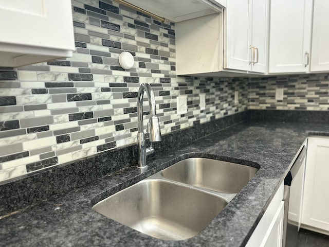 kitchen with white cabinetry, a sink, backsplash, and dark stone countertops