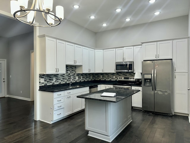 kitchen featuring dark wood finished floors, white cabinets, a kitchen island, appliances with stainless steel finishes, and a sink