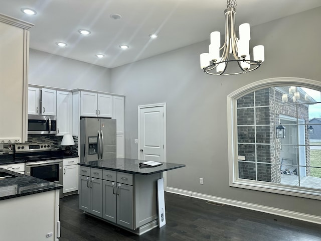 kitchen with dark wood-style floors, stainless steel appliances, hanging light fixtures, and backsplash