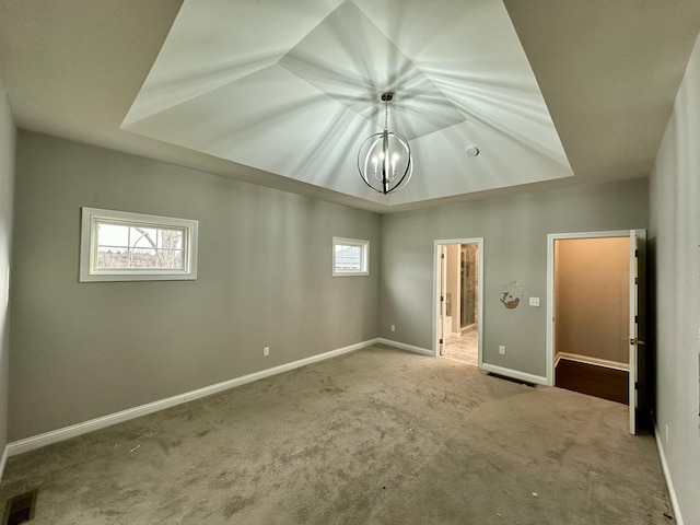 unfurnished bedroom with a tray ceiling, carpet, visible vents, and baseboards