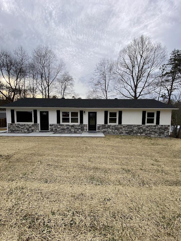 ranch-style house featuring stone siding