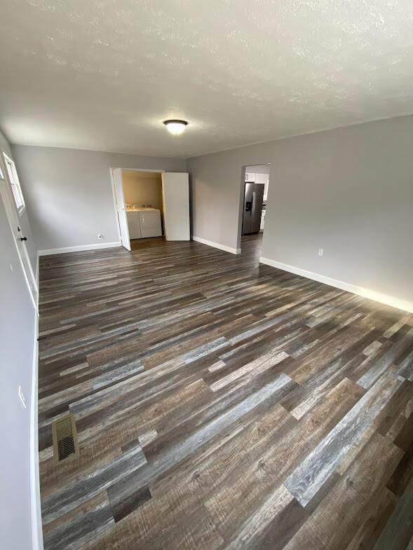 interior space featuring dark wood-style flooring, a textured ceiling, and baseboards