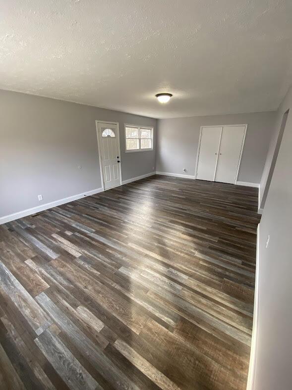 interior space featuring dark wood-style floors, baseboards, and a textured ceiling