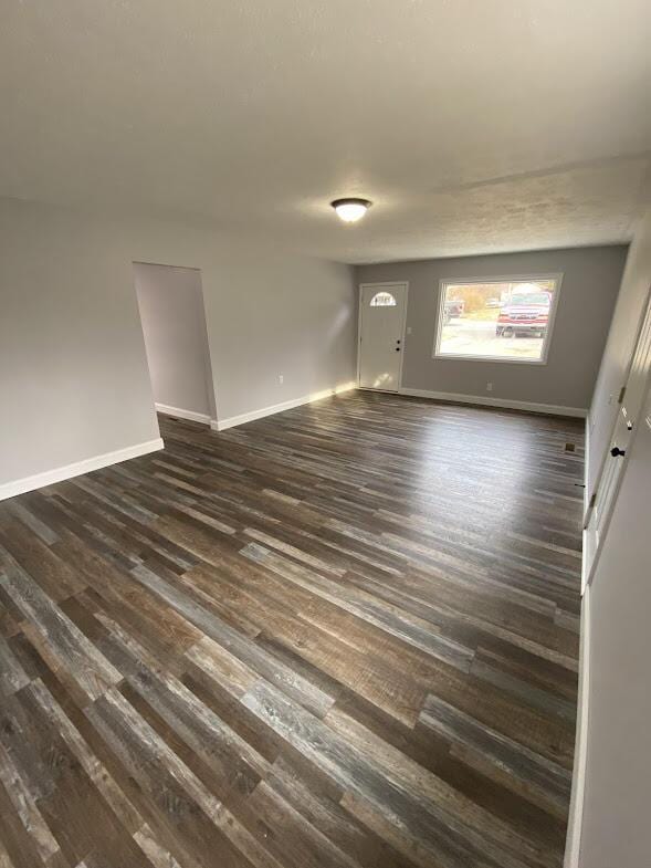 empty room featuring dark wood-style flooring and baseboards