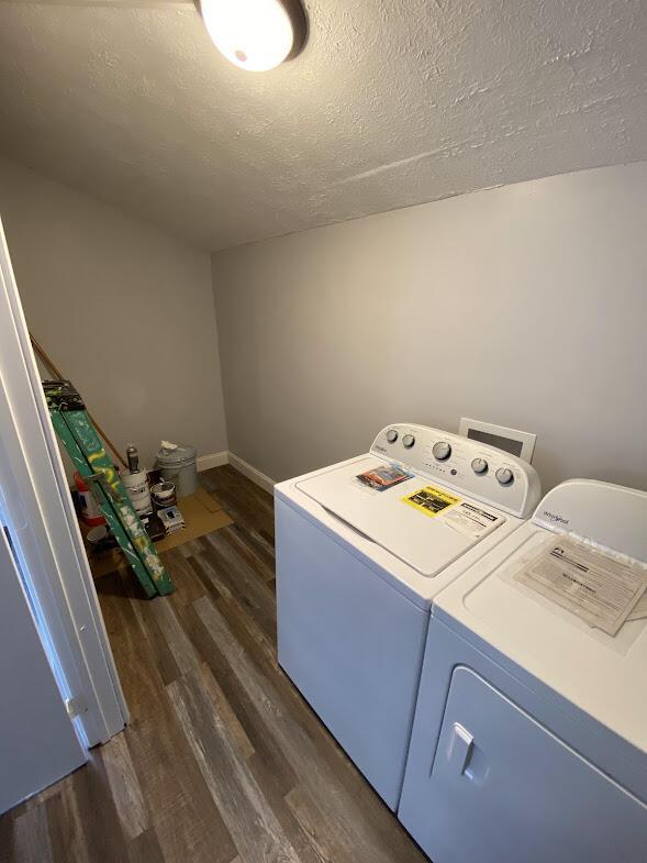 washroom featuring dark wood-type flooring, a textured ceiling, laundry area, independent washer and dryer, and baseboards