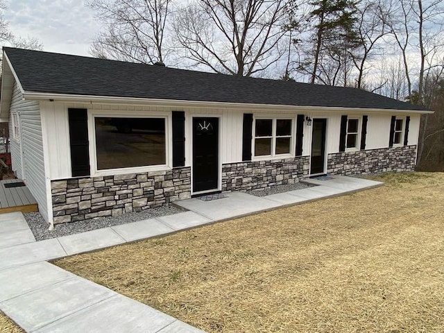 view of front of house with stone siding and roof with shingles