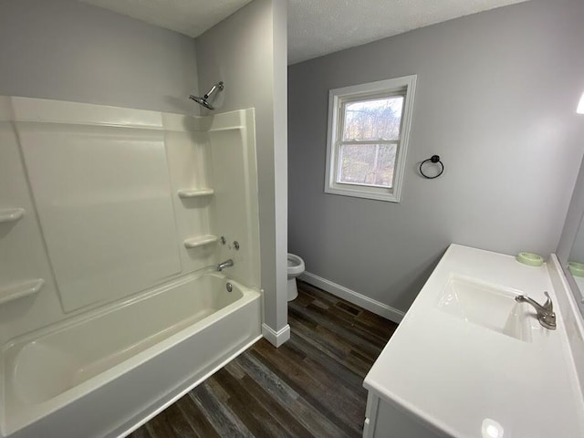 bathroom with baseboards, toilet, shower / tub combination, wood finished floors, and vanity