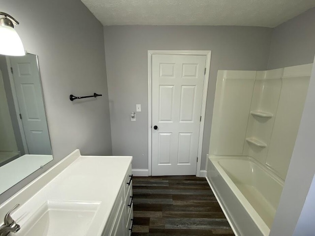 bathroom with shower / bathing tub combination, a textured ceiling, vanity, and wood finished floors