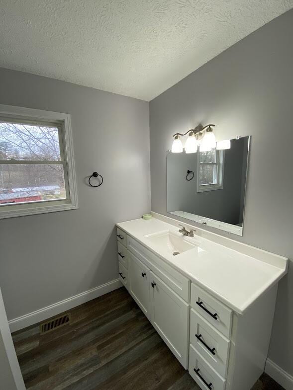 bathroom featuring a textured ceiling, visible vents, wood finished floors, and vanity