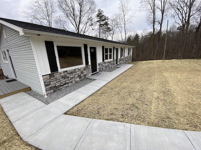 view of front facade with stone siding and a front lawn