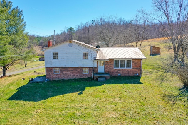 view of front of home with metal roof, a front lawn, crawl space, and brick siding