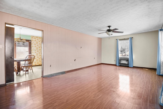 empty room featuring a textured ceiling, baseboards, and wood finished floors