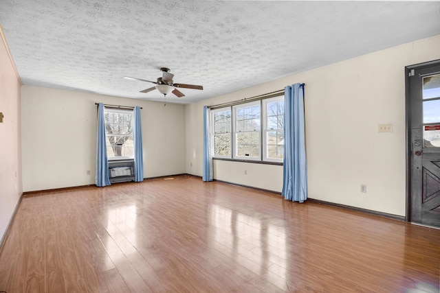 unfurnished room featuring ceiling fan, a textured ceiling, baseboards, and wood finished floors