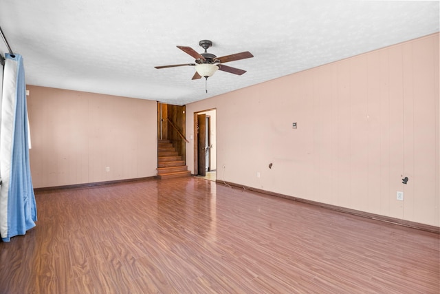 spare room featuring stairs, ceiling fan, a textured ceiling, and wood finished floors