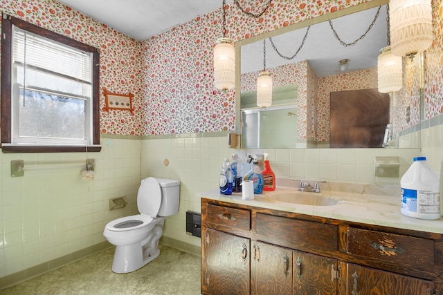 full bath with wainscoting, vanity, toilet, and wallpapered walls