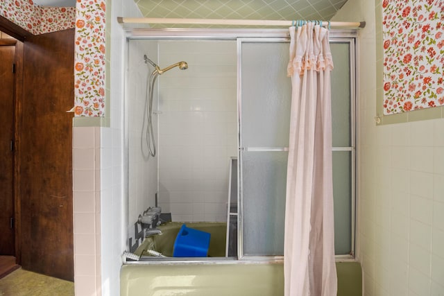 bathroom with tiled shower / bath combo and tile walls