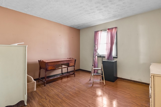 miscellaneous room with a textured ceiling, wood finished floors, and baseboards