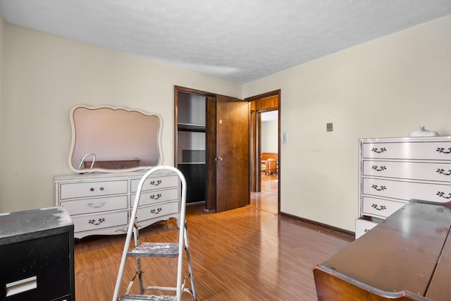 bedroom featuring a closet, a textured ceiling, baseboards, and wood finished floors