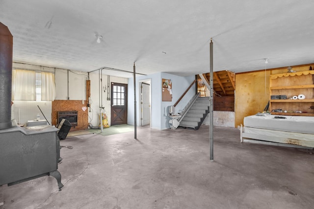 basement with a glass covered fireplace, heating unit, and stairs