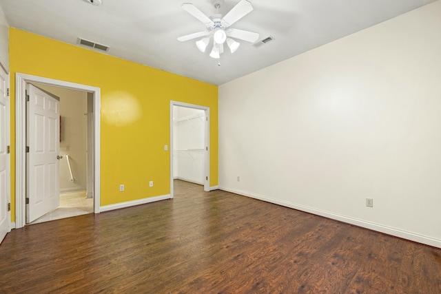 unfurnished bedroom featuring baseboards, a spacious closet, visible vents, and wood finished floors