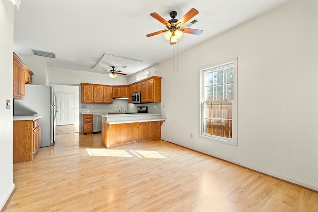 kitchen with brown cabinets, light countertops, visible vents, appliances with stainless steel finishes, and a peninsula