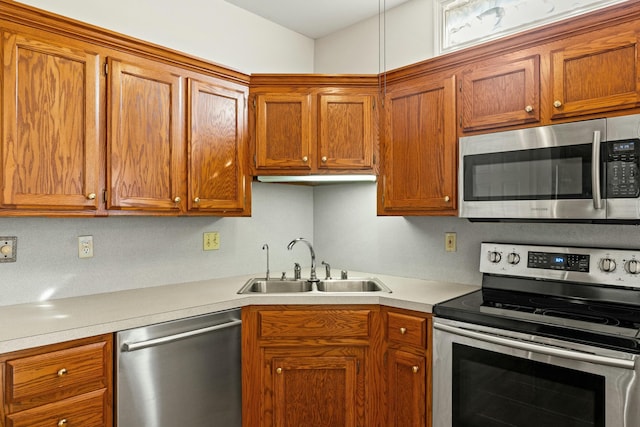 kitchen featuring stainless steel appliances, a sink, light countertops, and brown cabinets