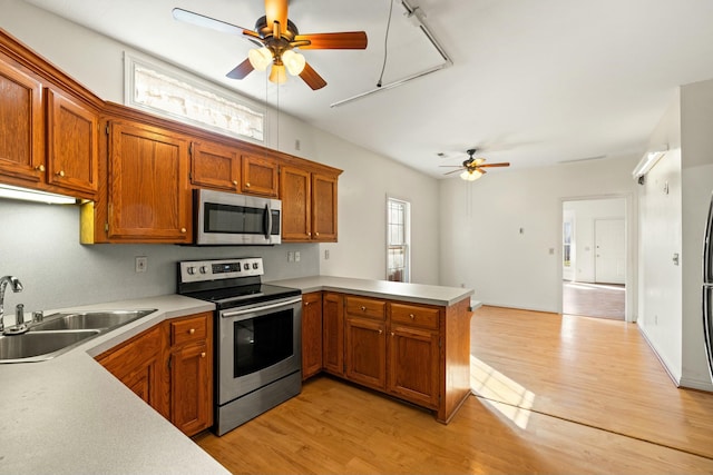 kitchen featuring a peninsula, appliances with stainless steel finishes, light countertops, and a sink