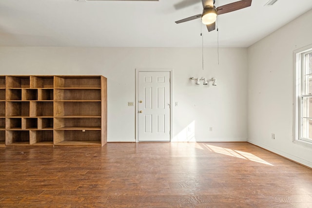 empty room with ceiling fan, baseboards, and wood finished floors