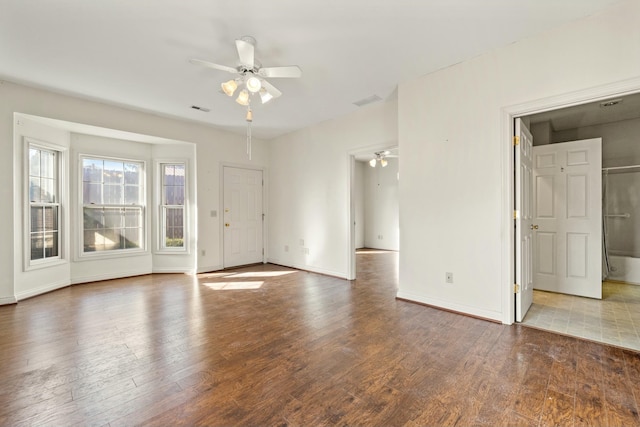 spare room with wood finished floors, a ceiling fan, and baseboards