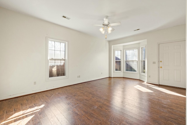 interior space featuring baseboards, wood-type flooring, visible vents, and a ceiling fan