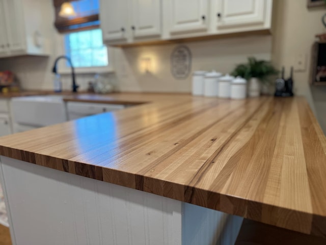 kitchen featuring butcher block counters, white cabinetry, and a sink