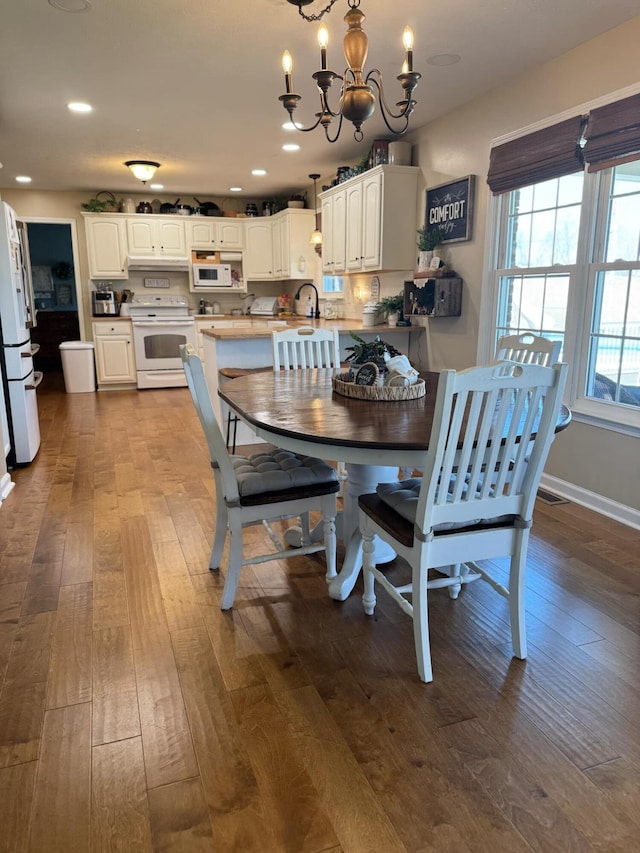 dining space featuring a chandelier, dark wood-type flooring, baseboards, and recessed lighting