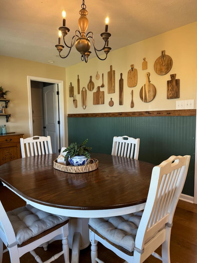 dining space with wood finished floors and an inviting chandelier