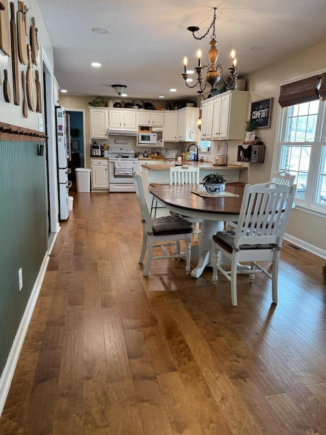 dining space featuring baseboards, visible vents, dark wood finished floors, an inviting chandelier, and recessed lighting