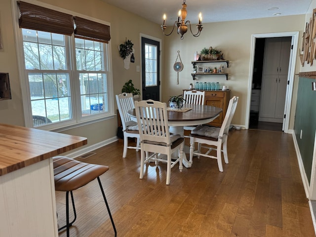 dining area featuring dark wood-style floors, visible vents, baseboards, and an inviting chandelier