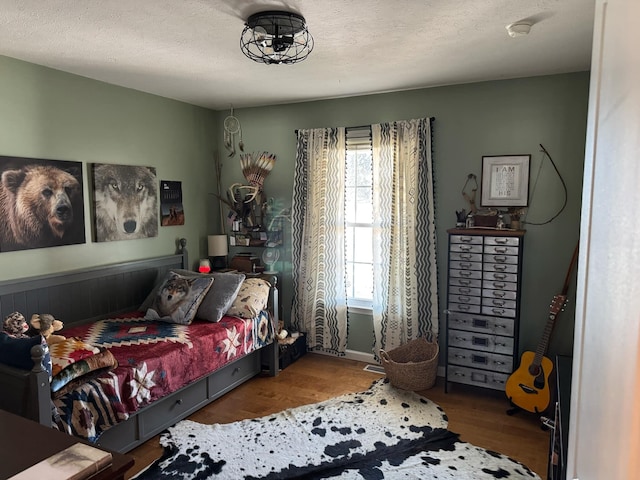 bedroom with a textured ceiling and wood finished floors