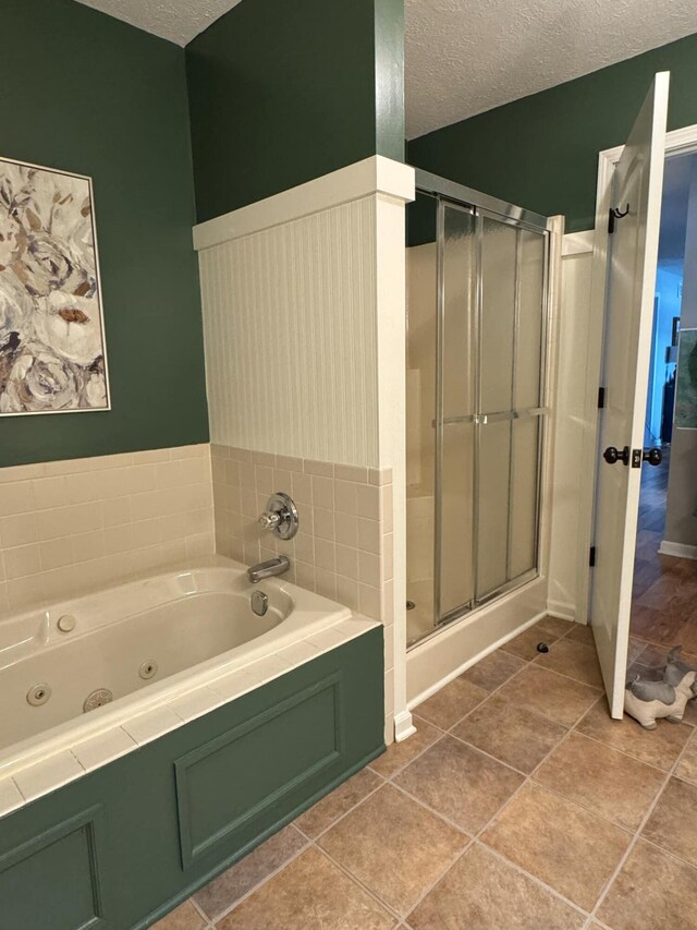 bathroom with a textured ceiling, a stall shower, a jetted tub, and tile patterned floors