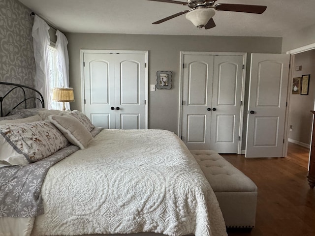 bedroom with ceiling fan, baseboards, multiple closets, and wood finished floors