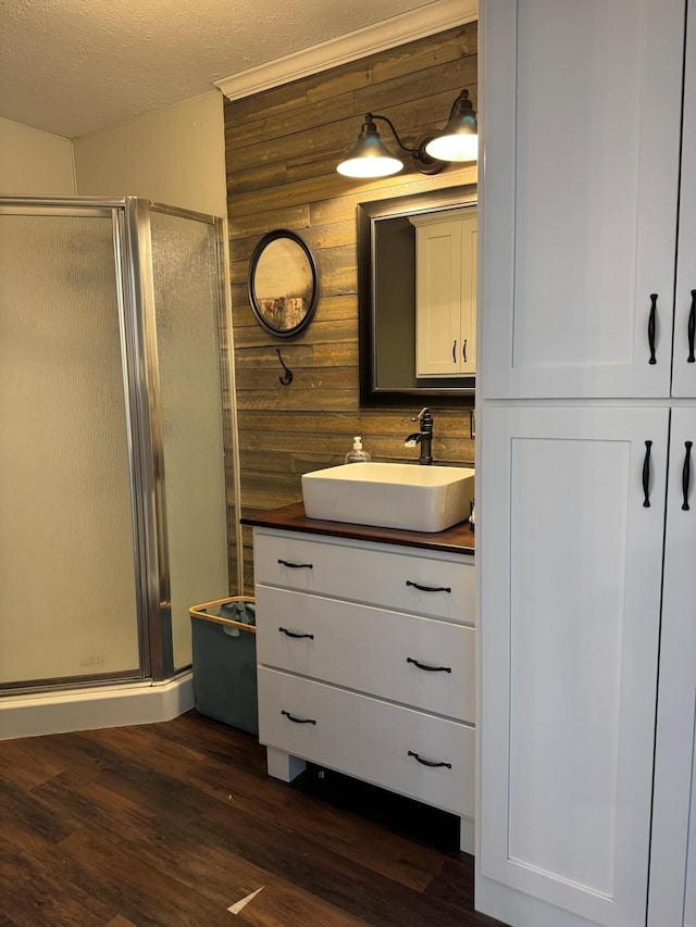 bathroom featuring wooden walls, a shower stall, vanity, and wood finished floors