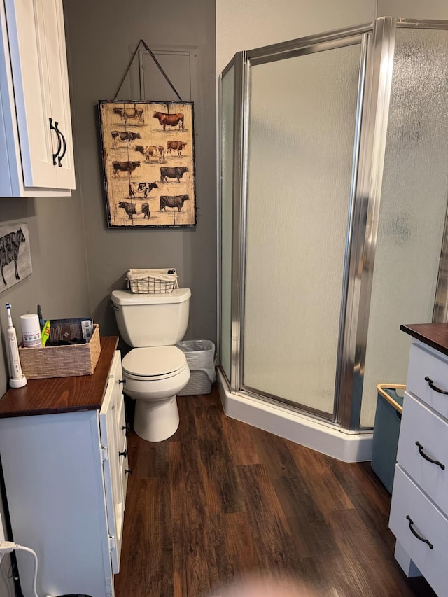 full bathroom featuring toilet, a shower stall, wood finished floors, and vanity