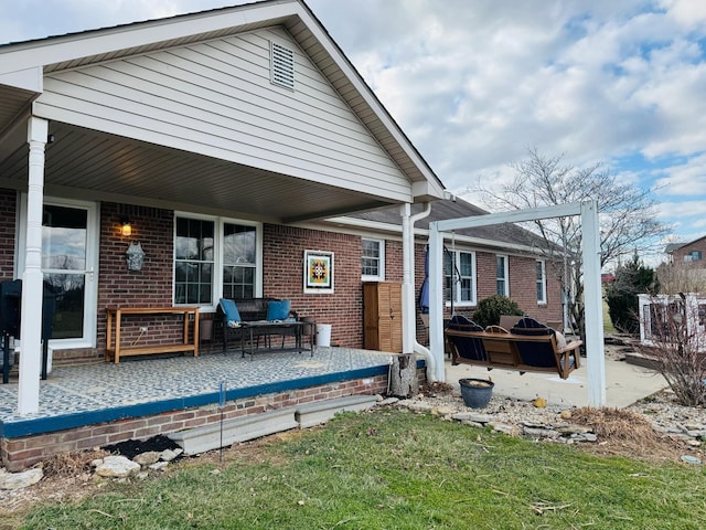 back of house with a patio area, brick siding, and a porch