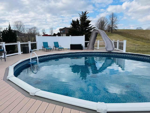 view of swimming pool with a fenced in pool, a water slide, and fence