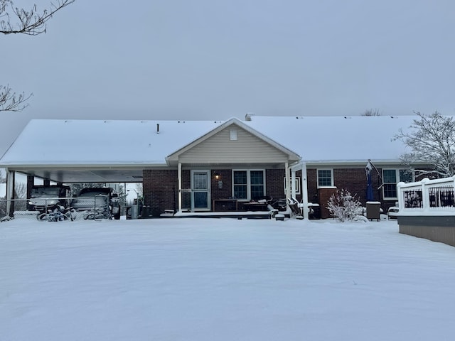 snow covered rear of property with brick siding